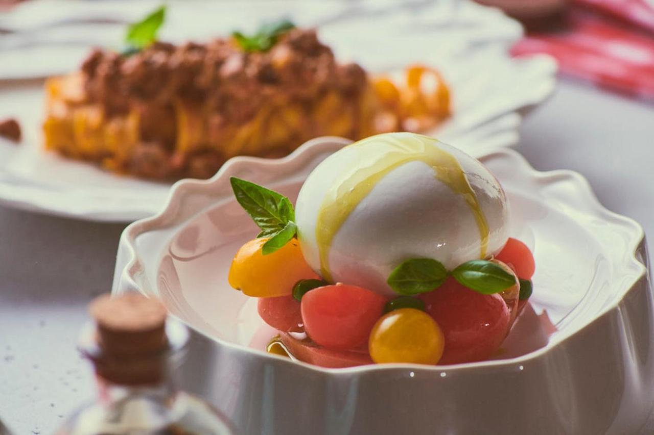 Five Jumeirah Village Dubai Buitenkant foto The photo showcases a beautifully presented dish featuring a large ball of fresh mozzarella cheese, sitting atop a colorful assortment of small tomatoes. The tomatoes are a mix of red and yellow, creating a vibrant visual contrast. Fresh basil leaves