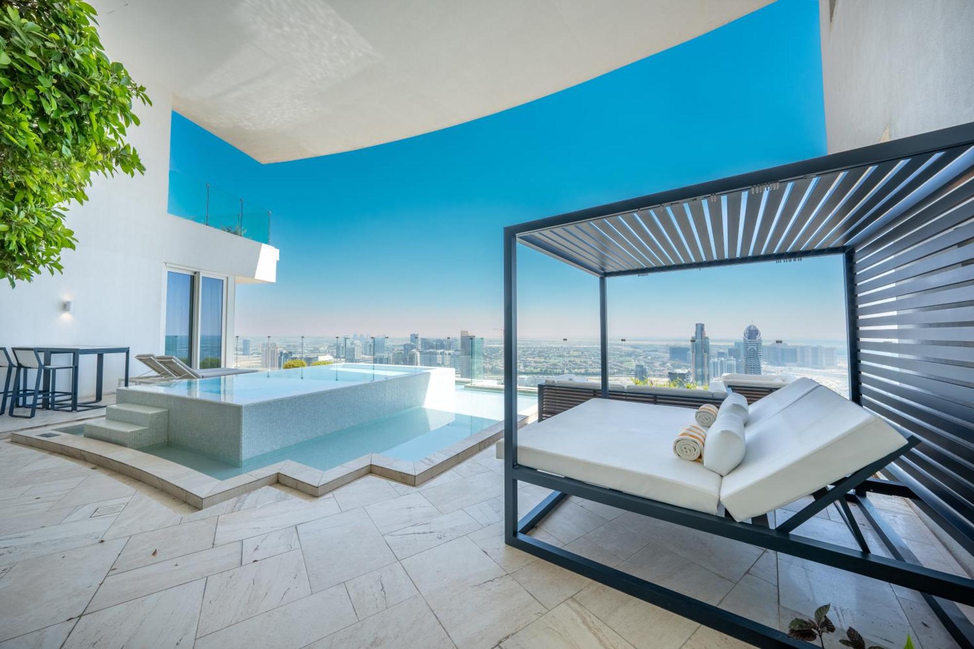 Five Jumeirah Village Dubai Buitenkant foto The photo shows a luxurious outdoor space that features a modern infinity pool and a stylish lounging area. The pool appears to be surrounded by sleek stone tiles, creating a beautiful contrast with the bright blue sky above. There is a contemporary 